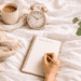 Woman writing in a notebook beside coffee and alarm clock during a calm 5 minute morning routine before work.